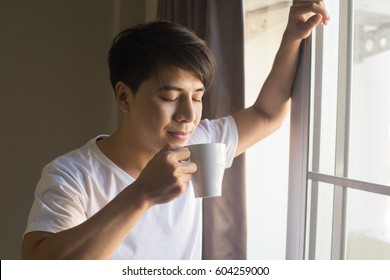 Asian Man Drinking Coffee With Coffee Cup In Morning Time.