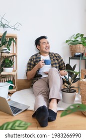 Asian Man Drinking Coffee In Green House.