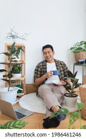 Asian Man Drinking Coffee In Green House.