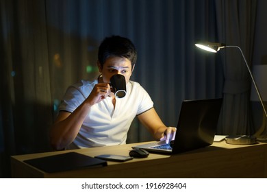 Asian Man Are Drinking Tea Or Coffee While Working In Late Night To Relieve Drowsiness And Make It Possible To Have A Strong To Work Again.
