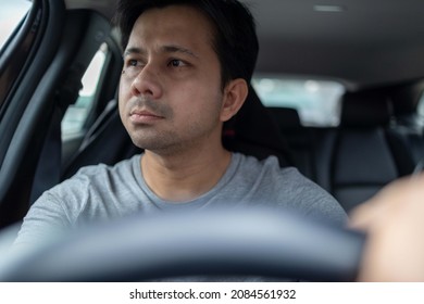 Asian Man Driving A Car Looking To The Side Of The Road