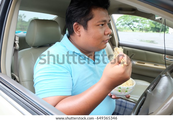  Asian man eat noodles in\
car