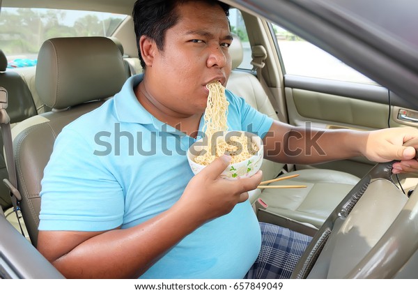  Asian man eat noodles in\
car