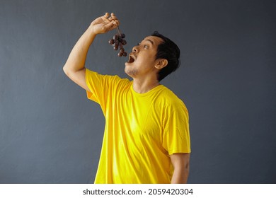 Asian Man Eating Fresh Purple Grapes For Healthy Life Style Concept