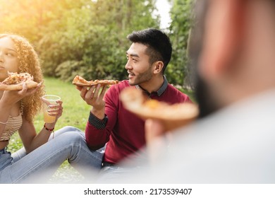 Asian Man Eating Pizza With Friends In The Park