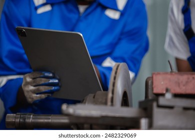 Asian man engineer using digital tablet workers check up usage of brake disc grinder. repair and maintenance service automobile.