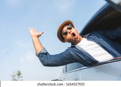 An Asian Man Is Enjoying His Trip. He Stretches Out Of The Car Window To Make Him Look Happy.