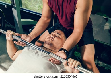 Asian man exercise bench press with Barbell lifting has a personal trainer support in the fitness club. Young man plus size weight training for loss weight. Loss weight exercise concept. - Powered by Shutterstock