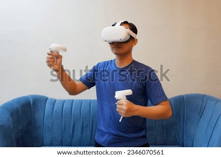 Asian man experiencing virtual reality goggles. VR helmet glasses surprised excited emotional, Virtual technology