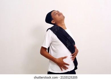 Asian Man Feel Very Full After Eating Too Much Food. The Man Holds His Stomach Full Of Food. Isolated On White Background