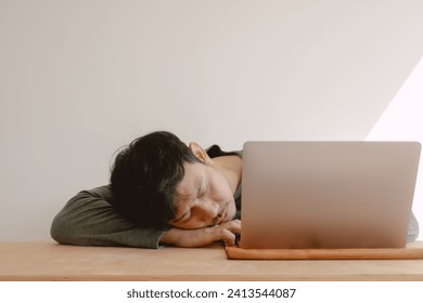 Asian man feeling bored tired and sleepy working with computer.