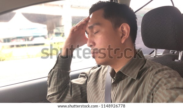 An\
Asian man feeling headache while driving  a car.\
