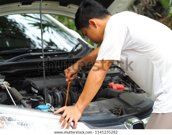 Asian man fix and check the engine interior of car\
in his house