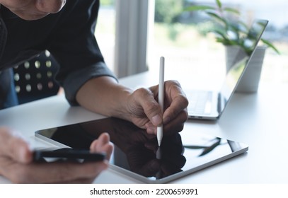Asian man freelancer working on computer devices at home office. Business man hand with stylus pen working on digital tablet, using mobile phone with laptop computer on office table at home. - Shutterstock ID 2200659391
