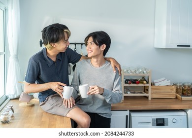 Asian Man Gay Family Sitting On Counter, Drink Coffee For Breakfast. Attractive Romantic Male Lgbtq Couple Celebrate Anniversary, Spend Time Have Dinner In Kitchen In House. Homosexual-LGBTQ Concept.