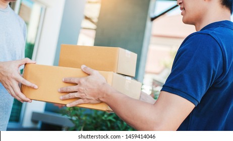 Asian Man hand accepting a delivery boxes from professional deliveryman at home