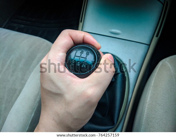 asian man hand holding black color leather\
manual car gear shift represent new or first time driver or people\
who love classic old vintage\
style