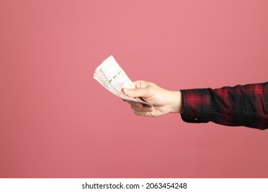 The Asian Man Hand Holding Money To Give For Someone On The Pink Background.