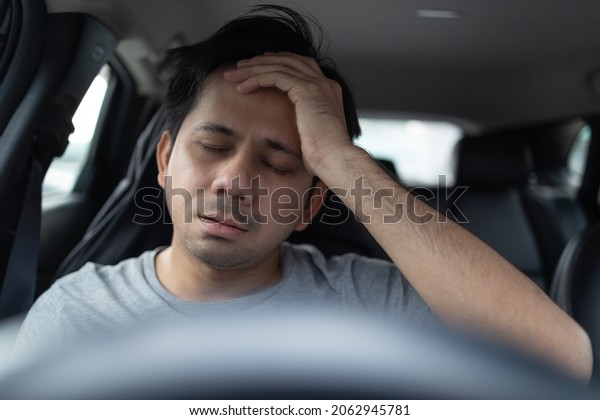 Asian man\
hand touches forehead with headache in\
car