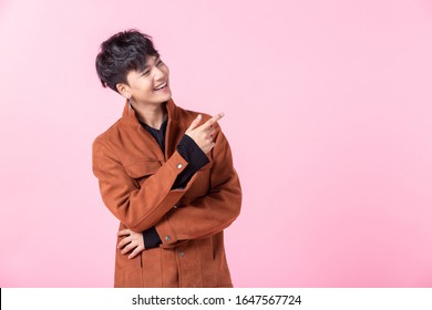Asian a man handsome young pointing with two hands and fingers to the side eyes looking at camera in love isolated on pink blank copy space studio background.
