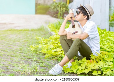 Asian man with the hat holding guitar ukulele at outdoor
