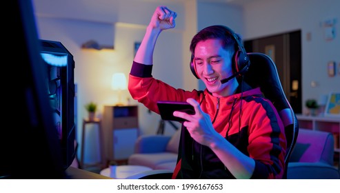 asian man have live stream and win mobile game on the smartphone with raising arm at home - Shutterstock ID 1996167653