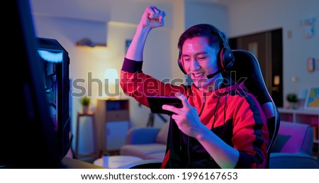 asian man have live stream and win mobile game on the smartphone with raising arm at home