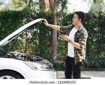 Asian man have some problem about the car he trying to fixed by himself.