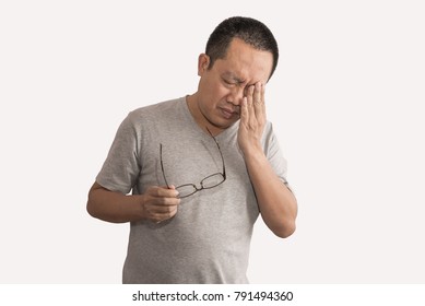 Asian Man Having Eye Pain With Migraines. Holding Eyeglasses, Image Is On Isolated White Background. Man Is 40-45 Years Old.