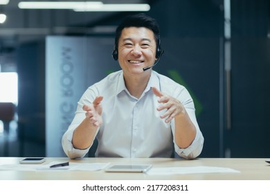 Asian Man With Headset Talking On Video Call, Looking Into Web Camera, Smiling Cheerfully And Gesticulating With Hands, Tech Support