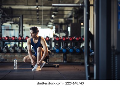 Asian man healthy preparing before workout training. Active Asian man tying shoelaces on sports shoes. Young male athlete legs in sneakers and hands tying shoelaces in fitness gym. - Powered by Shutterstock