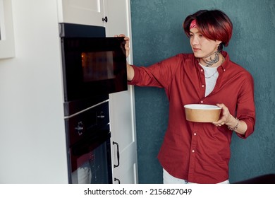 Asian Man Heating Food In Microwave At Home