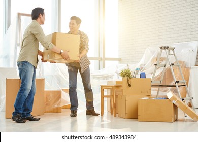 Asian Man Helping His Coworker To Carry Cardboard Box