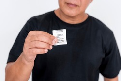 An Asian Man In His Middles Ages Displays A Small Packet Of Silica Gel. He Is Wearing A Simple Black T-shirt And Isolated On A White Background.