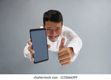 Asian Man Hold Smartphone And Show Thumb Up Isolated On Gray Background Above Top View