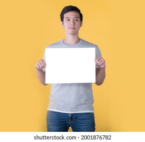 Asian man holding blank billboard isolated on yellow background - Powered by Shutterstock