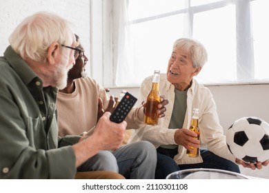 Asian Man Holding Football Near Interracial Friends With Beer At Home