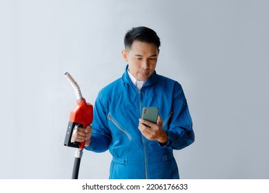 Asian Man Holding A Gas Nozzle And Mobile Phone, Fuel Consumption, Petrol Cars, Fluctuating Oil Prices, Using Renewable Fuel To Drive.