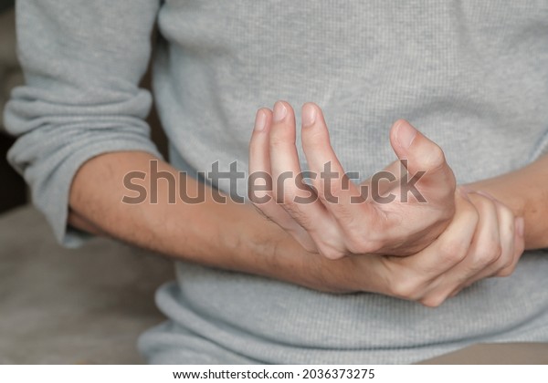 Asian man\
holding hand with muscle weakness, numbness and paralysis symptoms\
after vaccination. Guillain Barre syndrome rare cause by autoimmune\
disorder concept. Selective\
focus.