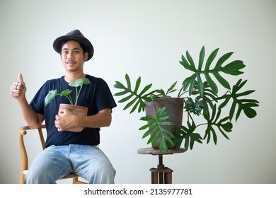 Asian man holding houseplants at bedroom and thumbs up.smiling confident.plant focus