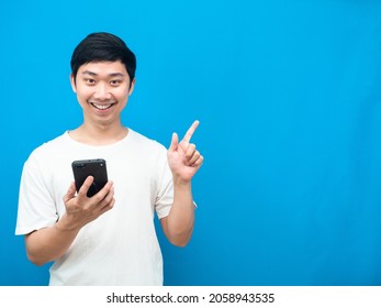 Asian Man Holding Mobile Phone Happy Smile And Point Finger At Copy Space Blue Background