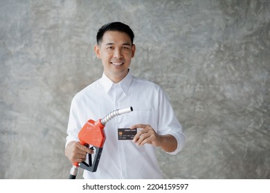 Asian Man Holding Petrol Dispenser And Credit Card, Fuel Consumption, Petrol-fueled Cars, Volatile Fuel Prices, Use Of Alternative Fuels For Driving.