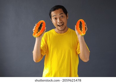 Asian Man Holding Two Pieces Of Papaya