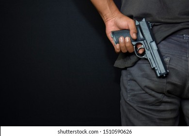 asian man holds a gun. Gun in his hand from the back isolated on black background.