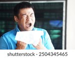 Asian man holds white tissue paper, going to sneeze ,cough, runny nose. Concept, Health problem. Health care. Catch a cold. Allergy symptom.Cover mouth when cough or sneeze to stop spreading of germs.