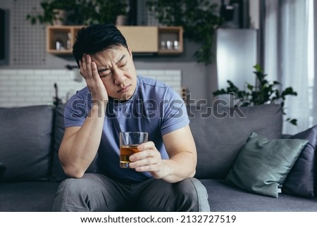 Asian man at home alone, depressed drinking strong alcohol, single man