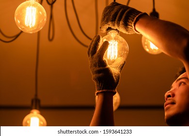 Asian man / house owner cleaning or changing vintage light bulb. House maintenance concept