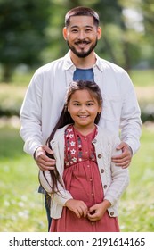 Asian Man Hugging Preteen Daughter In Park