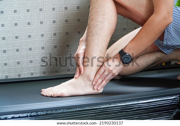 Asian man\
hurts his ankle while running on a treadmill,concept of not wearing\
shoes while running on a\
treadmill