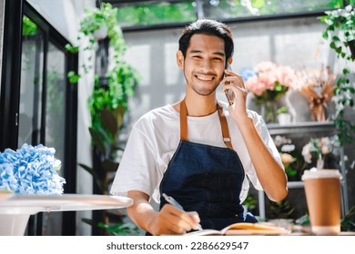 Asian man influencer or SME owner people smile work on home video camera selfie shoot.Smiling female florist talking on mobile phone. Young woman working at  shop with Open sign. - Powered by Shutterstock